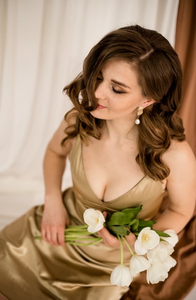 Wearing a white tube dress, holding a white bouquets of roses
